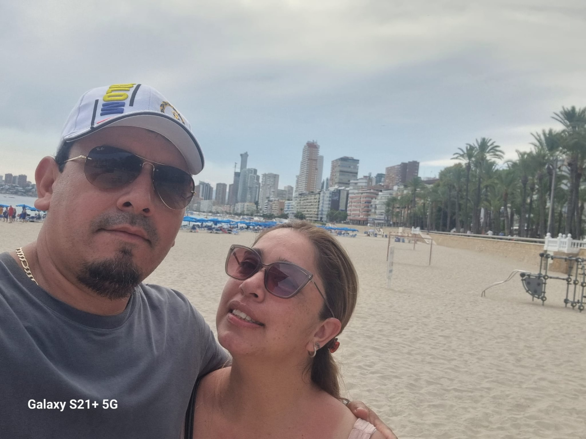 Ezequiel y Yiseth en la playa con la ciudad de fondo